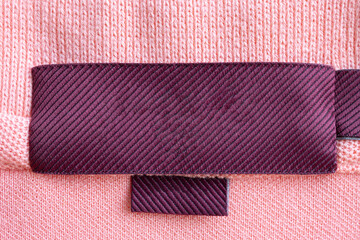 Blank red laundry care clothes label on pink fabric texture background