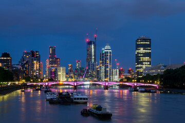 Lambeth bridge over river Thames and the slyline of Vauxhall district with modern buildings and towers illuminated at night in South London, UK