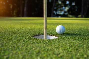 Golf ball on green grass in the evening golf course with sunshine background.