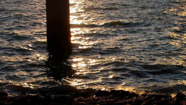 Sun setting behind a pole reflecting in the water