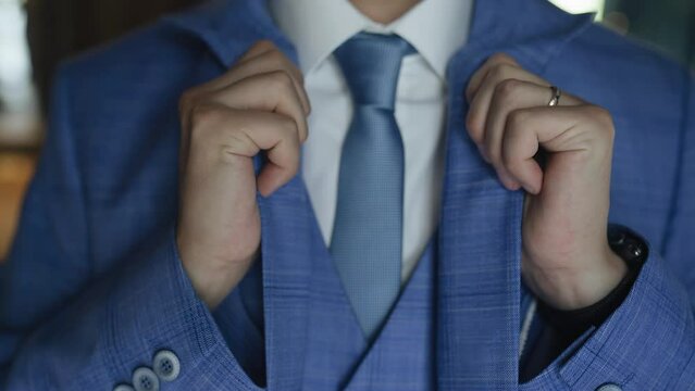A man adjusts his blue suit while going to a meeting or event. Shooting in close-up