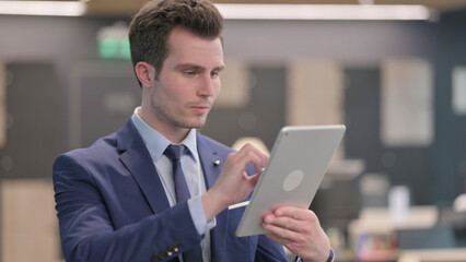 Portrait of Attractive Businessman using Tablet in Office