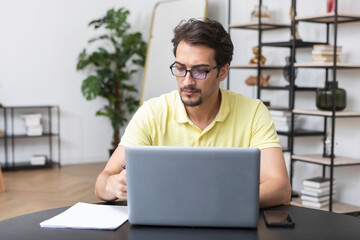 Serious businessman sitting at the table at home and working. Distant work concept