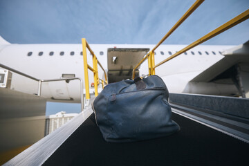 Loading of luggage to airplane. Blue bag on conveyor belt at airport..