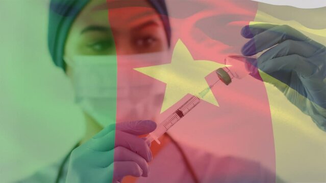 Animation of flag of cameroon over african american female doctor wearing face mask
