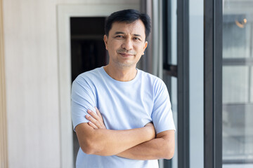 Smiling asian man looking happy at camera, cross arms chest confident in the office