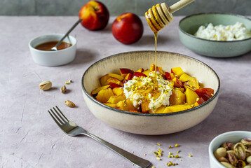 Healthy fruit salad with nectarine, ricotta cream with pistachios and honey
