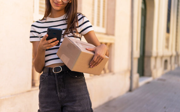 Anonymous female courier photographing parcel on street