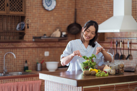 Woman preparing yummy salad in kitchen
