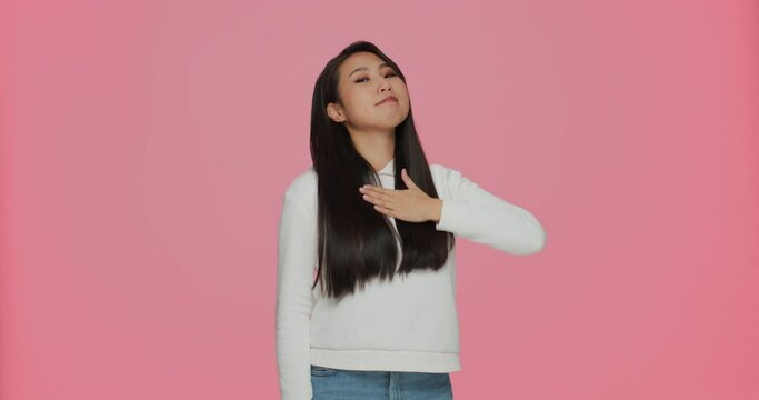 Ambitious self -confident young asian girl pointing by fingers on herself, proud of achievements on pink background