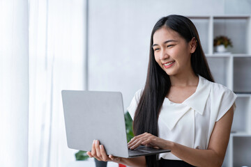 Beautiful Asian businesswoman holding a laptop computer and looking at the camera.