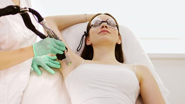 Cosmetologist does laser hair removal of the armpits, laser procedure at beauty studio or clinic. Body epilation treatment and skin care concept.	
