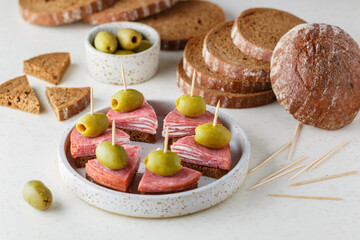 Rye bread sandwiches with salami, cream cheese and olives. Antipasti. Canapes. A delicious snack for gourmets. Selective focus