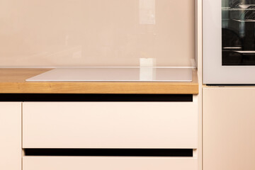 Fototapeta na wymiar Modern bright white and beige kitchen closeup. Induction cooker hob built into the kitchen worktop
