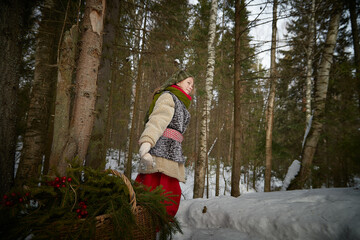 Nice cute teenager girl in old peasant clothes with hot fur coat and shawl in cold winter forest...
