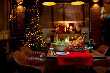 Roasted Turkey, wine, vegetables salad and various food are set on table for family to celebrate together at night and Christmas tree also set in the room for Christmas holiday.