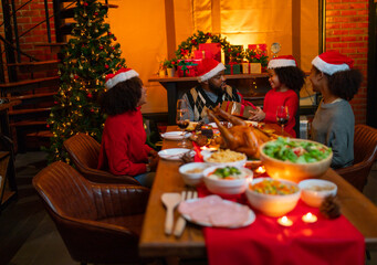 African American little girl give gift box to her father and the other member in family join to celebrate together during Christmas holiday and night dinner.