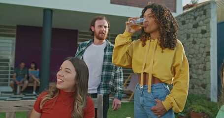 A group of friends having lunch in the backyard. Diverse people conversing talking during home garden party