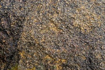 Raw gray granite rock texture background. Fragment of natural stone wall