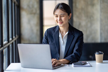 Asian business woman working on laptop and taking notes at the office.