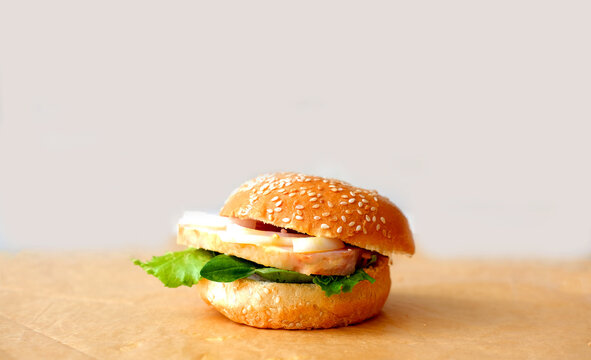 Sandwich with bacon and onion on semmel roll served on texture of old newspaper. Bavarian burger the leberkase semmel. Creative space for Sandwich Day design. Close-up