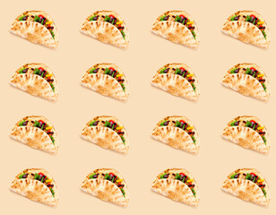 Pattern of Corn tortilla tacos with vegetable filling on background in shades of beige. Traditional dish of Mexican cuisine or World Vegan Day. Creative space for packaging design. Close-up