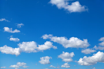 Naklejka na ściany i meble Fluffy white clouds in blue summer sky, perfect background.