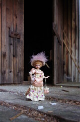 porcelain doll with a hat in front of a wooden house