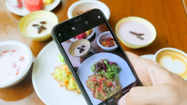Man hand take photos of breakfast by mobile phone