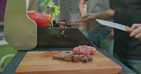 Closeup meat on cutting board. Chef preparing barbecue grill at backyard party garden