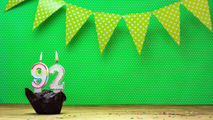 happy birthday with decorations festive garlands with muffin on a green background with polka dots. Copy space. Beautiful happy birthday background with burning candles with number 92