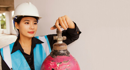 Asian female foreman inspects metal oxygen cylinders pressure welding and oxygen cylinder valves...