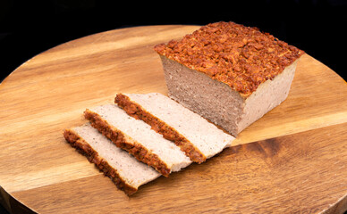 Meat pate, sliced on a wood cutting board, on black background. Traditional Polish baked meat...