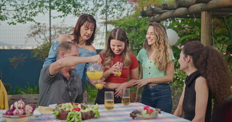 Joyful smiling people celebrating holidays in home garden party. Group of friends and family in backyard barbecue. Parents and adults daughters together for holidays