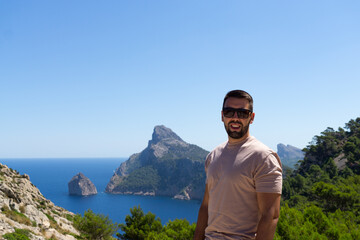 Young male tourist with sunglasses at the viewpoint es Colomer in Mallorca, Spain.