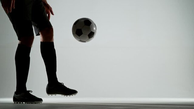 Super slow motion of soccer player dribbling with the ball. Shot on white studio background. Filmed on high speed cinema camera, 1000fps. Speed ramp effect.