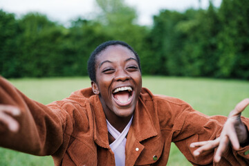 Short-haired young woman happy and sending a hug in the park outdoors
