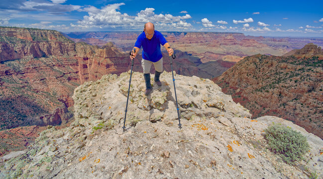 A hiker climbing on the edge of a cliff along Buggeln Hill Trail halfway between Grandview Point and the Sinking Ship at Grand Canyon Arizona.