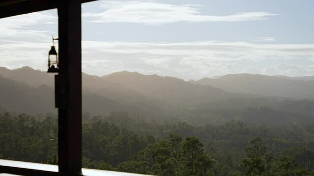 View on mountains with dense misty forest from the moutain hotel terrace. Beautiful scenery with soft warm sunlight