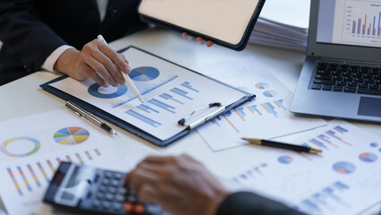 Business team together to make investment plan at the meeting. Close-up of business advisor pointing to graph and chart analyzing company financial report.