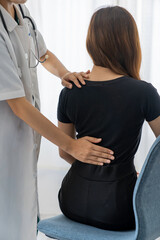 Female doctor doing physiotherapy to treat back. Female office worker back pain treatment. Doctor,...