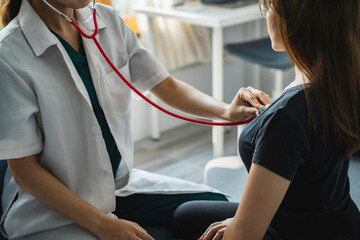 female doctor uses a stethoscope to measure the patient's heart to check for abnormalities in the...