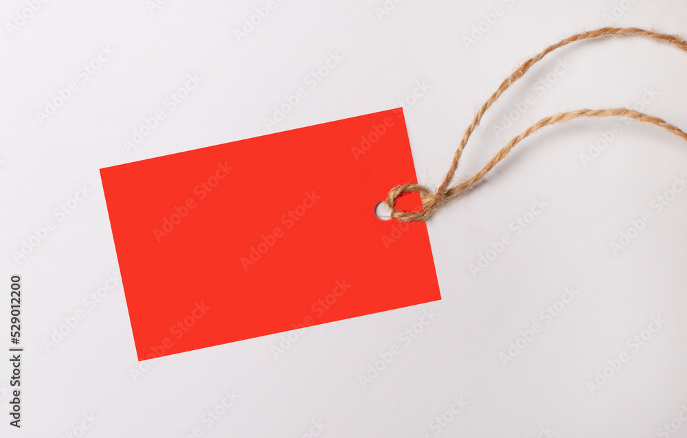 Aufkleber red rectangular empty price tag with place to insert text on a string on a white background. copy sp