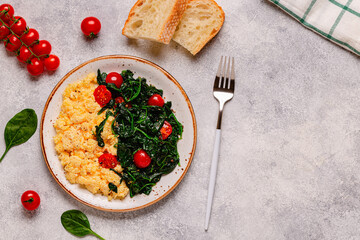 Cooked omelette and spinach with tomatoes on a light background