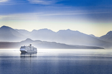 A cruise ship cruising a fjord in Alaska on a summer evening