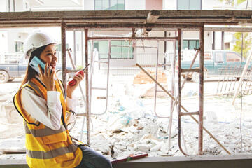Female architect foreman oversees the construction talks on smartphones and radios reports construction progress housing project and communicates with the project owners with satisfaction.