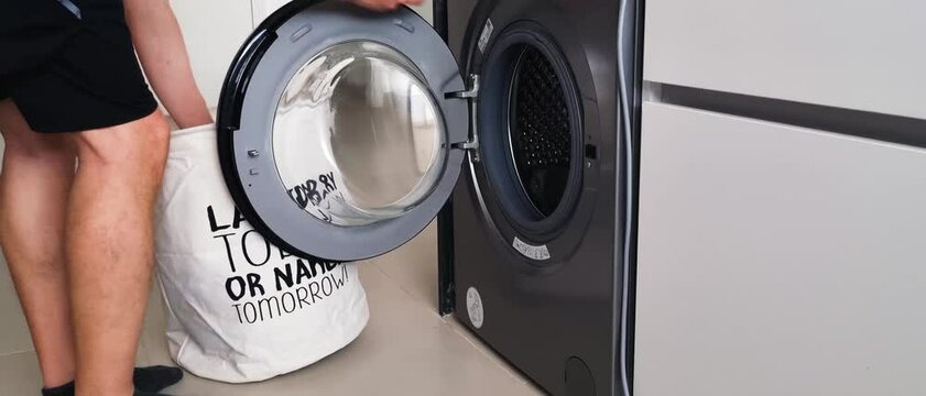 Footage of a laundry being loaded into the washing machine.