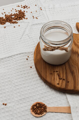 Jar with alternative buckwheat milk on wooden board. Animal-friendly vegan food. mindful eating. taking care of your health. No lactose, no allergy dairy product. Soft focus, blurred background