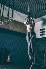 Fit blonde woman climbing the rope training working out in Gym