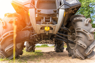 Front and bottom view of the ATV standing on sandy ground - obrazy, fototapety, plakaty
